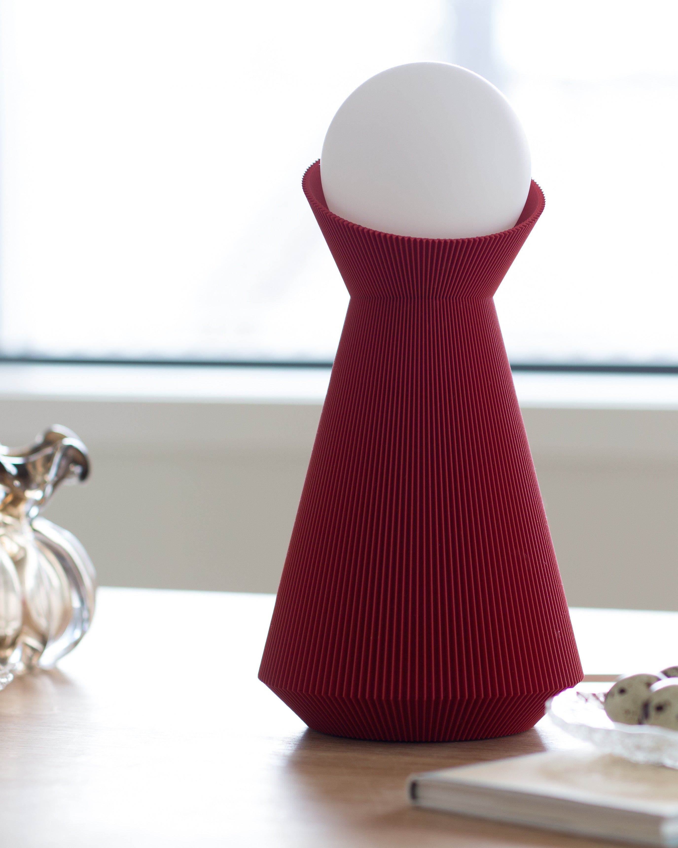 Deep red sera lamp with a white bulb on a wooden surface
