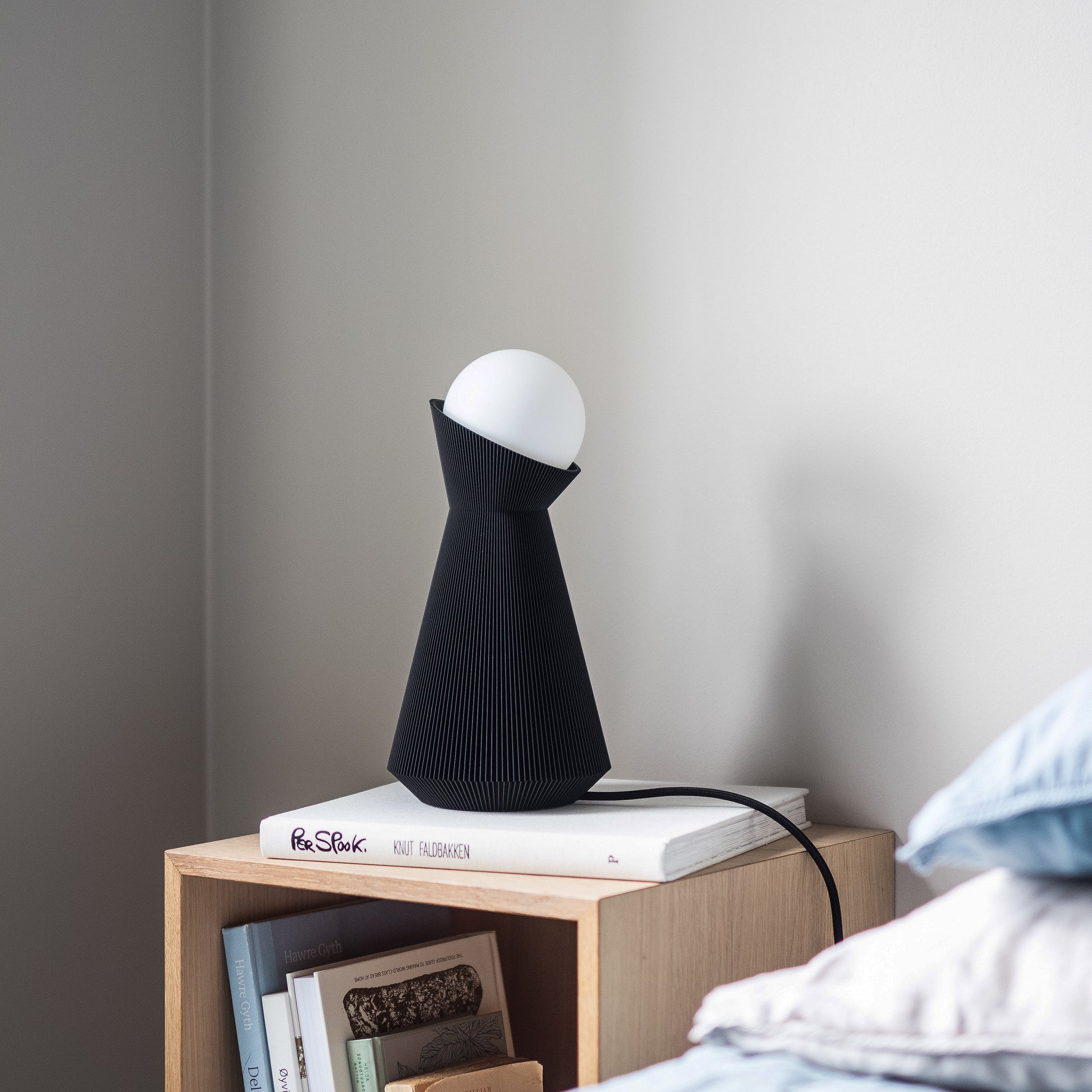 Charcoal sera lamp on a nightstand with dekorative books in daylight