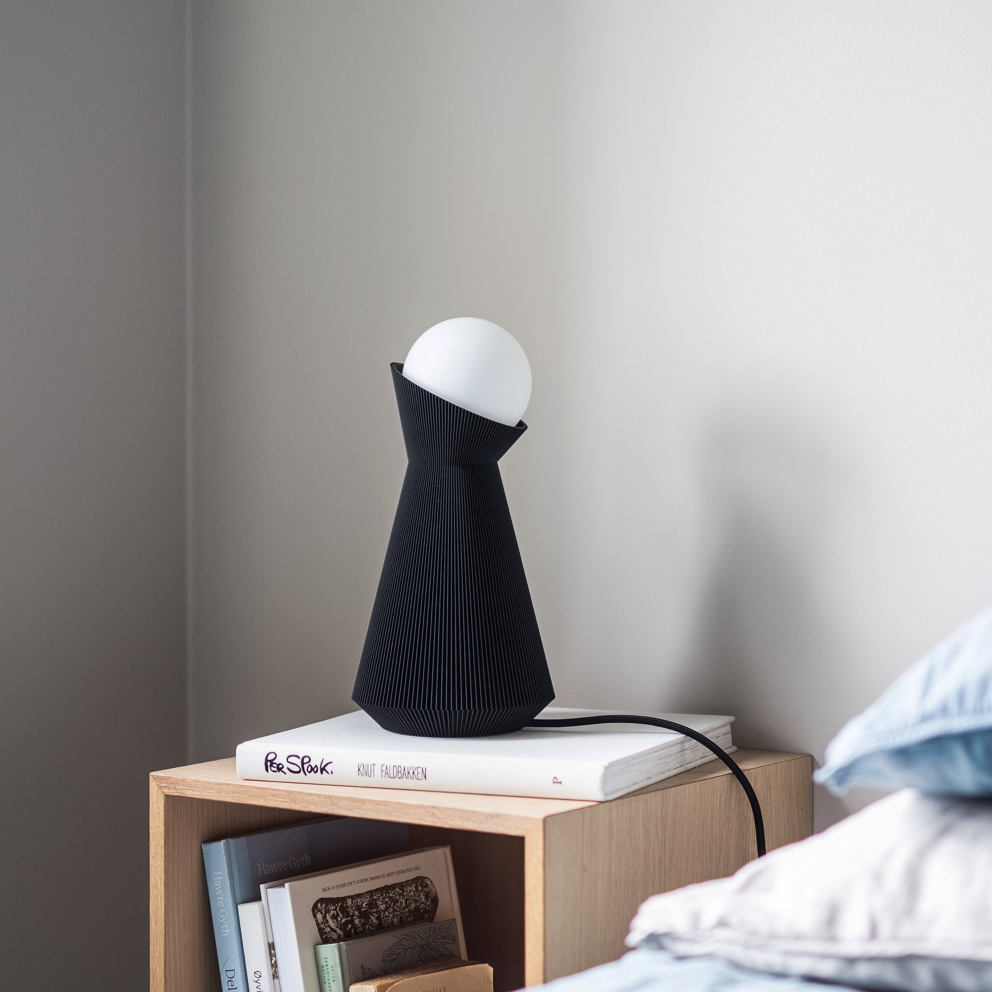 Charcoal sera lamp on a nightstand with dekorative books in daylight