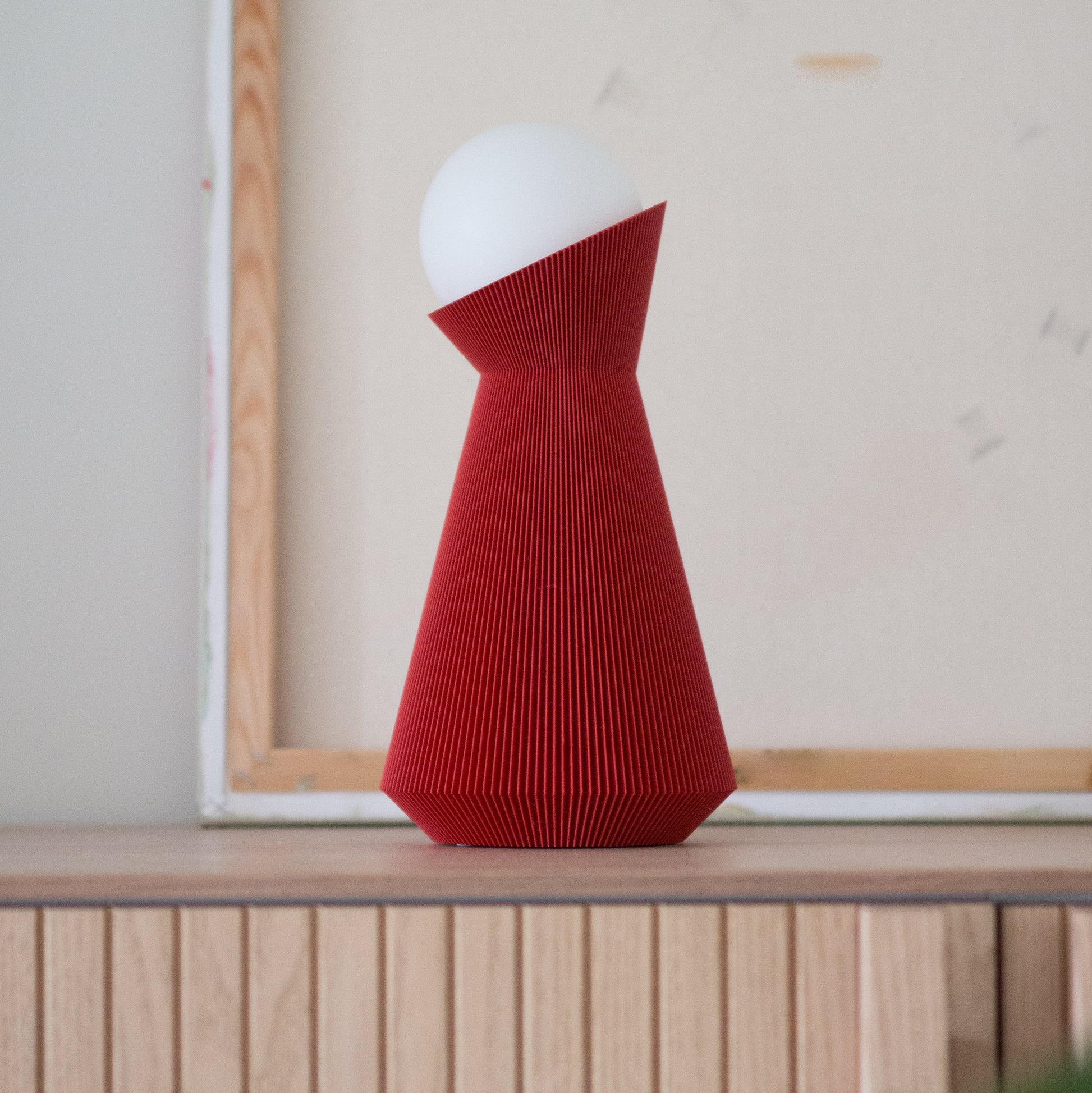 Deep red sera lamp on a wooden surface with a light gray wall in the background