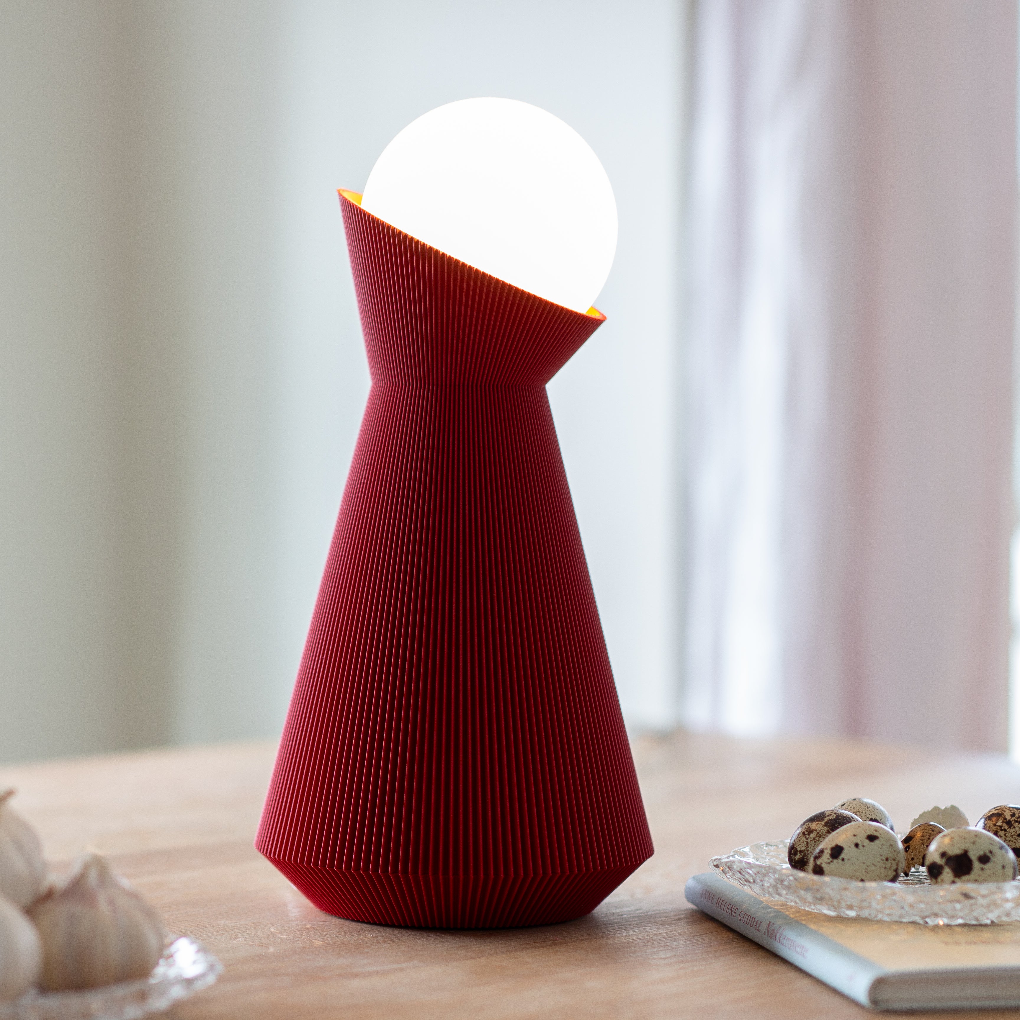 Deep red sera lamp with a white bulb on a wooden surface