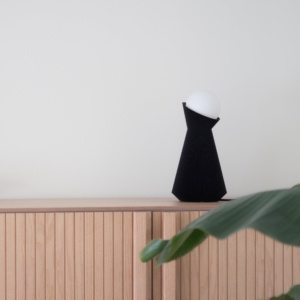 Charcoal Sera lamp on a wooden cupboard with a plant