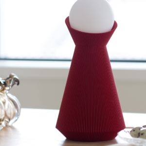 Deep red Sera lamp with a white bulb on a wooden surface
