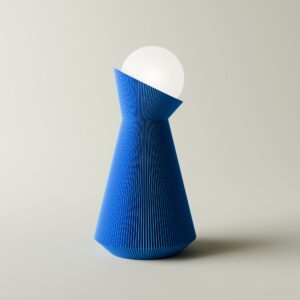 Denim blue Sera table lamp with a white bulb on a light grey background