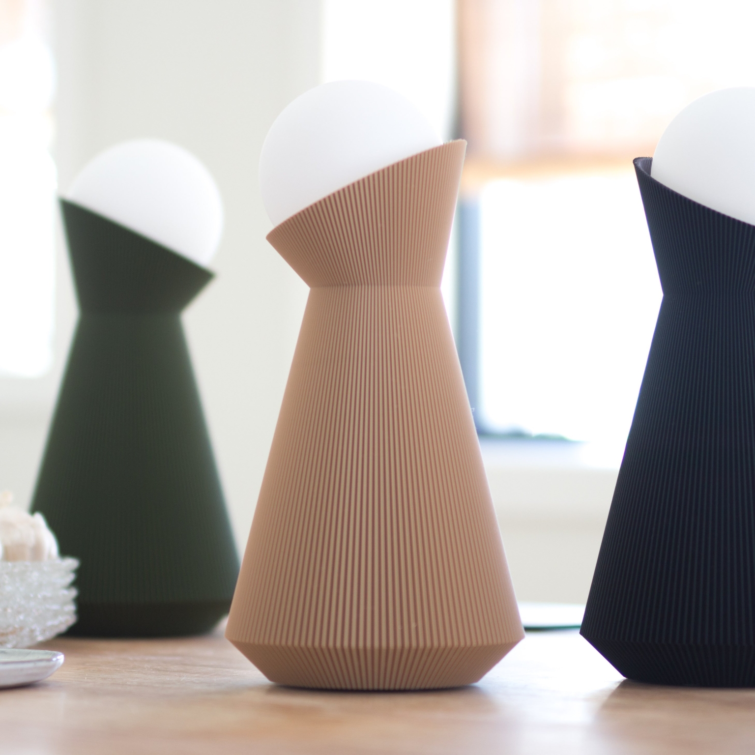 Sera lamps in forest green, desert tan and charcoal on a wooden table